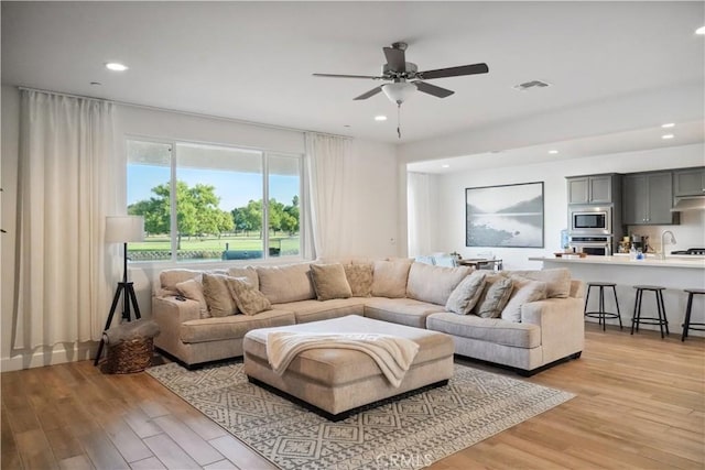 living room with light hardwood / wood-style flooring and ceiling fan