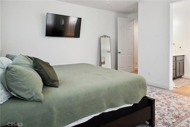 bedroom with ensuite bath and light hardwood / wood-style floors