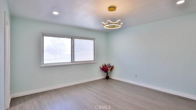 spare room featuring hardwood / wood-style floors and a chandelier