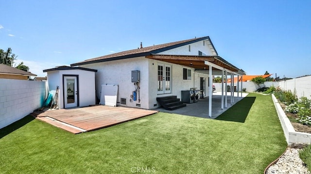 back of property featuring a wooden deck, a patio, and a lawn