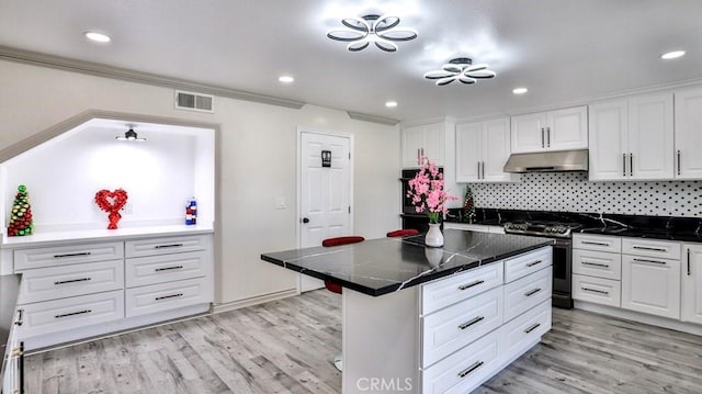 kitchen featuring crown molding, stainless steel stove, decorative backsplash, and white cabinets