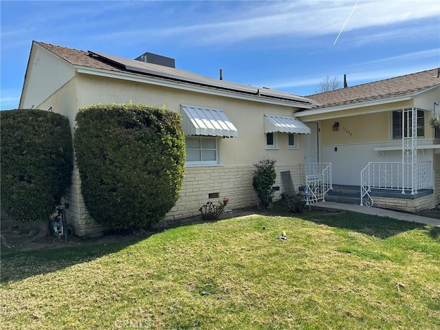 exterior space featuring crawl space, roof mounted solar panels, and a lawn