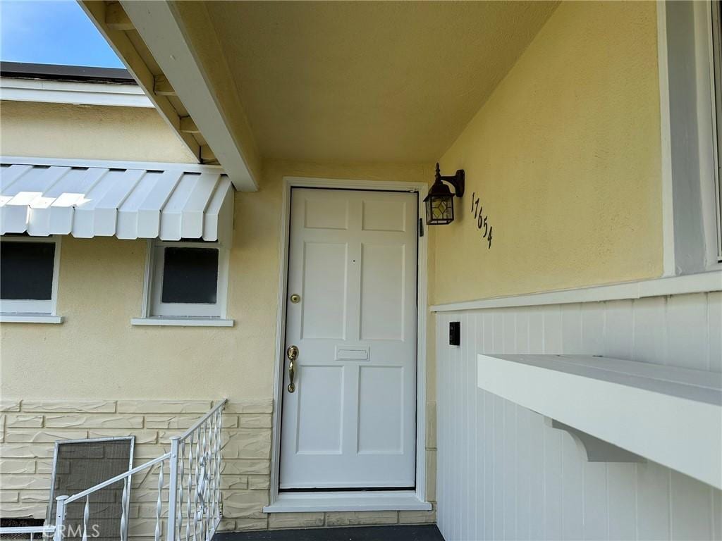 view of exterior entry featuring stone siding and stucco siding