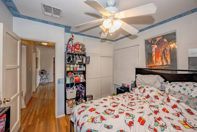 bedroom with ceiling fan, a closet, wood finished floors, and visible vents