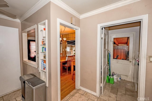 hallway with stone tile flooring, a notable chandelier, baseboards, and crown molding