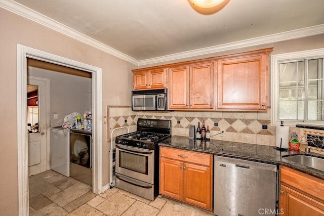 kitchen with stainless steel appliances, separate washer and dryer, a sink, stone tile flooring, and crown molding