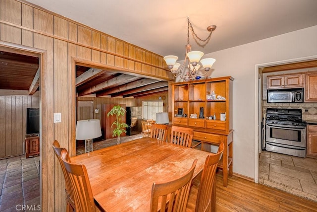 dining area featuring a notable chandelier and wood walls