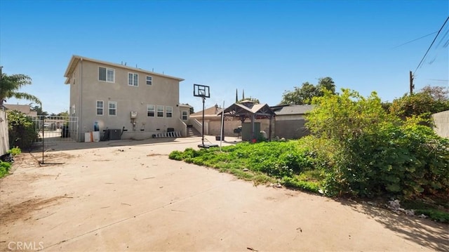 back of property featuring a gazebo, fence, and stucco siding