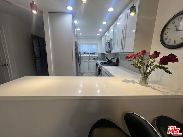 kitchen featuring stainless steel appliances, white cabinets, a kitchen breakfast bar, and kitchen peninsula