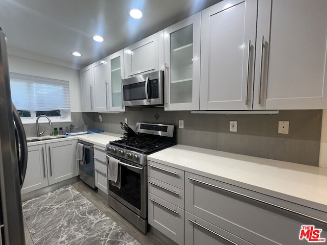 kitchen with white cabinetry, sink, decorative backsplash, stainless steel appliances, and dark wood-type flooring