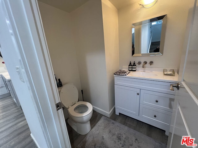 bathroom featuring wood-type flooring, toilet, and vanity