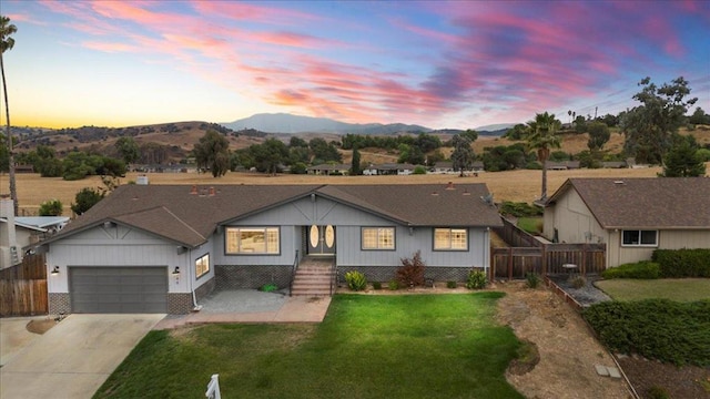 single story home featuring a mountain view, a yard, and a garage