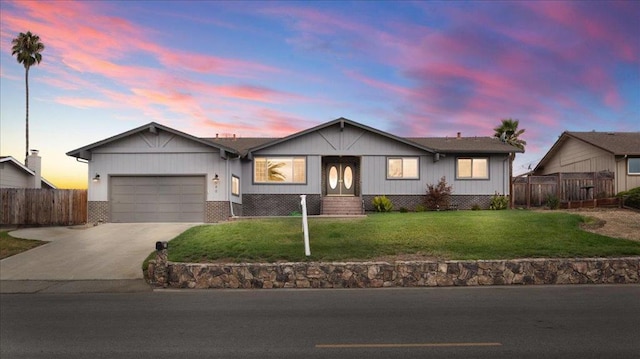 ranch-style house with a garage and a lawn