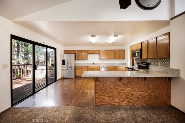 kitchen with lofted ceiling, sink, appliances with stainless steel finishes, backsplash, and kitchen peninsula