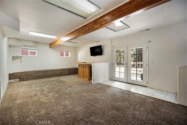 unfurnished living room featuring light carpet, french doors, and beamed ceiling