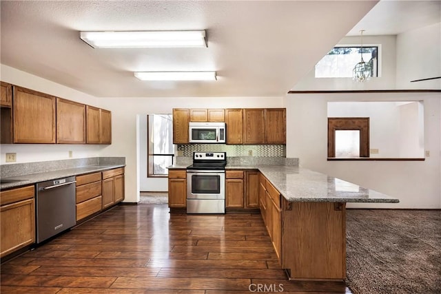 kitchen featuring pendant lighting, dark wood-type flooring, a breakfast bar, stainless steel appliances, and kitchen peninsula