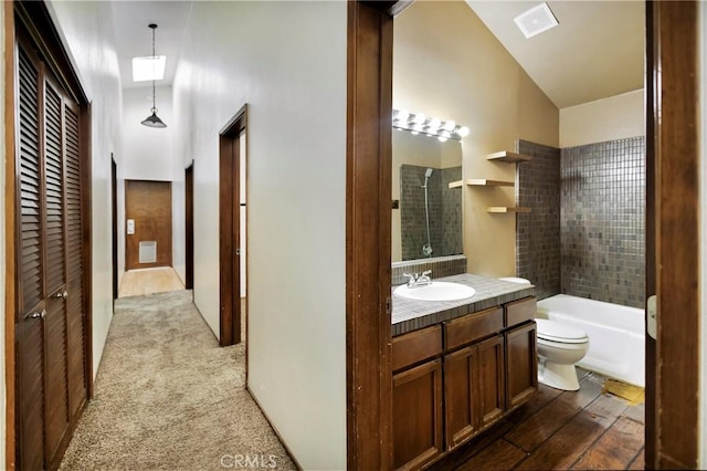 full bathroom featuring vanity, tiled shower / bath combo, lofted ceiling, and toilet