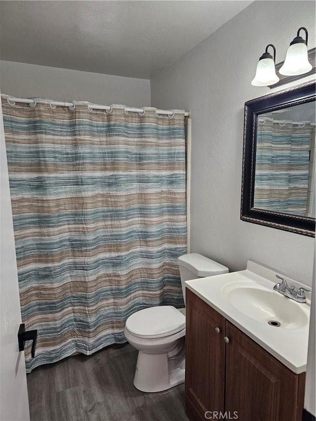 bathroom featuring vanity, hardwood / wood-style floors, walk in shower, and toilet