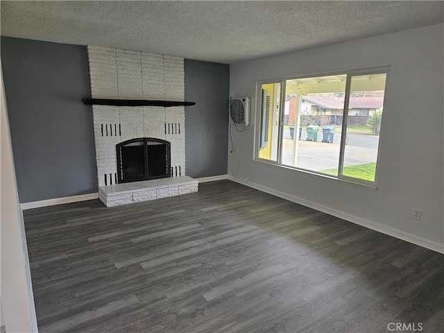 unfurnished living room with dark wood-type flooring, a brick fireplace, and a textured ceiling