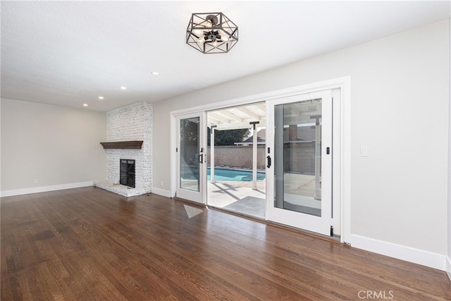 unfurnished living room with a large fireplace, dark wood-type flooring, and french doors