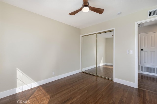 unfurnished bedroom with dark hardwood / wood-style flooring, a closet, and ceiling fan