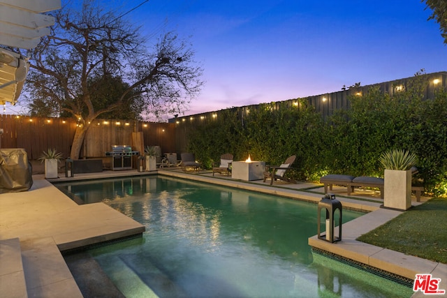 pool at dusk featuring a fire pit and a patio area