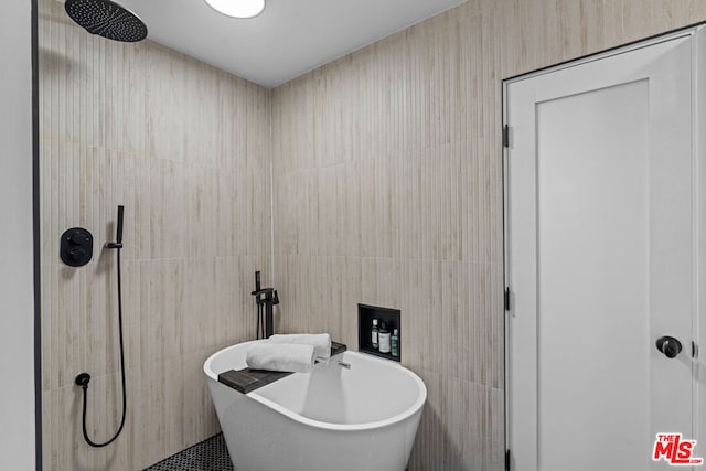 bathroom featuring plus walk in shower and tile walls