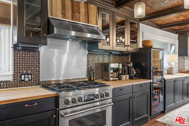 kitchen featuring butcher block counters, backsplash, stainless steel range with gas cooktop, and exhaust hood