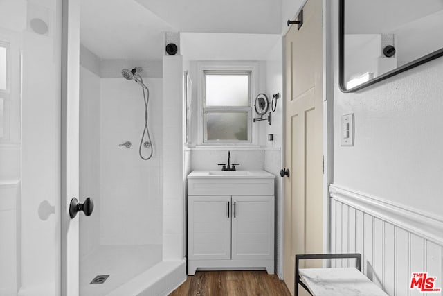 bathroom featuring vanity, wood-type flooring, and tiled shower