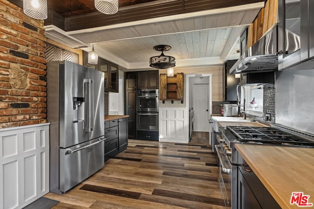 kitchen with high end appliances, dark wood-type flooring, decorative light fixtures, and butcher block countertops