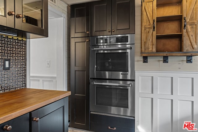 kitchen featuring stainless steel double oven, wooden counters, and dark brown cabinetry