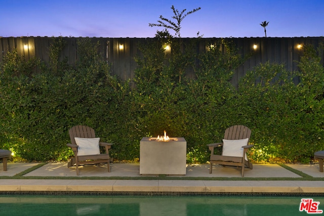 pool at dusk with a patio area and an outdoor fire pit