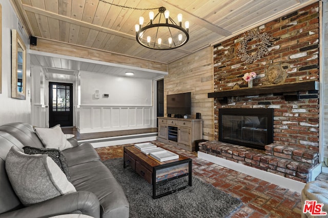 living room featuring a notable chandelier, a brick fireplace, wooden ceiling, and beam ceiling