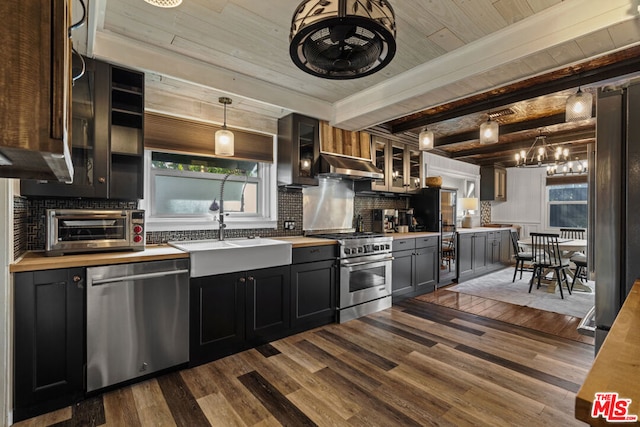 kitchen with sink, dark wood-type flooring, appliances with stainless steel finishes, tasteful backsplash, and decorative light fixtures