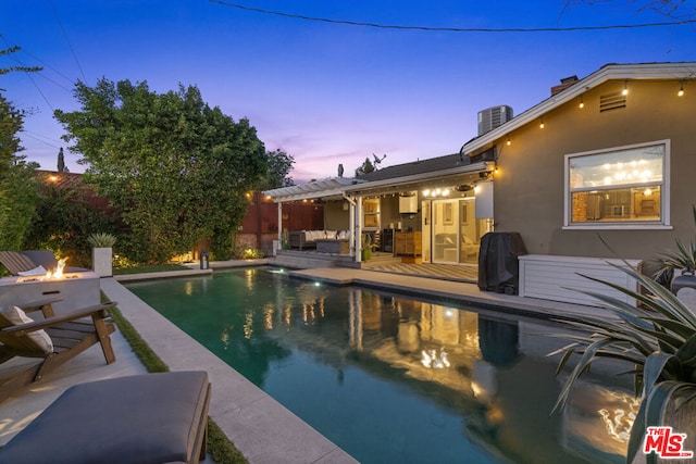 pool at dusk with a patio area and an outdoor fire pit