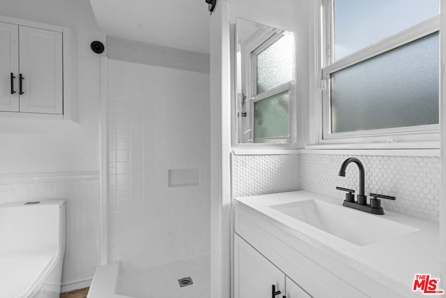 bathroom with a tile shower, vanity, and toilet