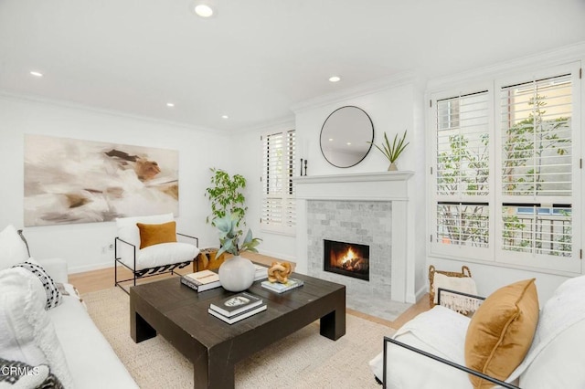 living room featuring ornamental molding, a fireplace, and light wood-type flooring