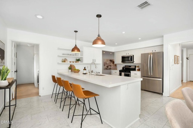 kitchen featuring pendant lighting, sink, white cabinets, a kitchen bar, and stainless steel appliances