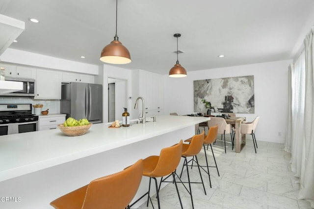 kitchen with white cabinetry, appliances with stainless steel finishes, and decorative light fixtures