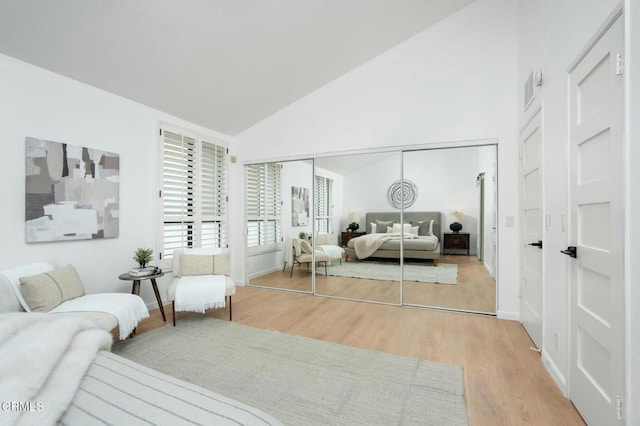 bedroom with vaulted ceiling, light wood-type flooring, and a closet