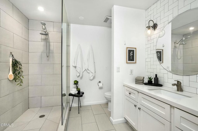 bathroom with vanity, tiled shower, and toilet