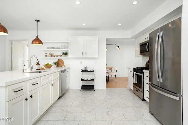 kitchen featuring white cabinetry, appliances with stainless steel finishes, sink, and hanging light fixtures