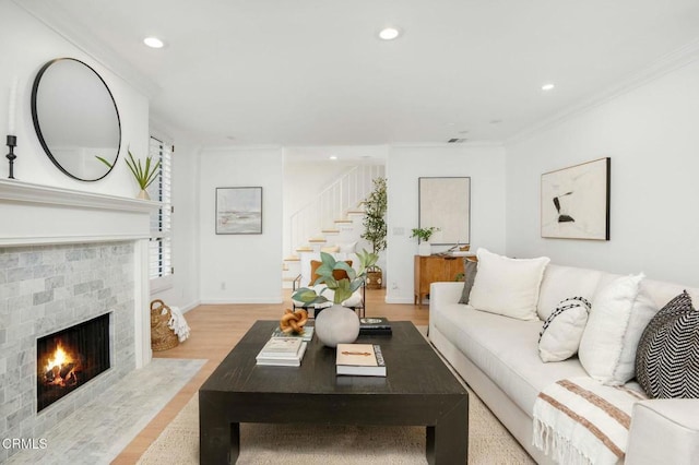 living room with a tiled fireplace, ornamental molding, and light hardwood / wood-style floors