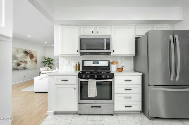 kitchen featuring stainless steel appliances, tasteful backsplash, white cabinets, and light hardwood / wood-style floors