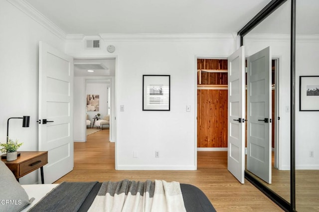 bedroom featuring ornamental molding, light wood-type flooring, and a closet