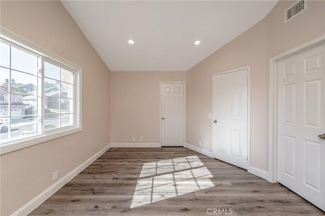 unfurnished bedroom with vaulted ceiling and wood-type flooring