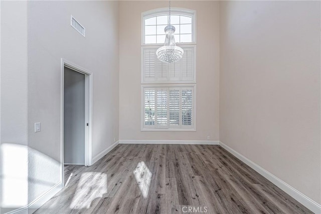 unfurnished room with a towering ceiling and wood-type flooring