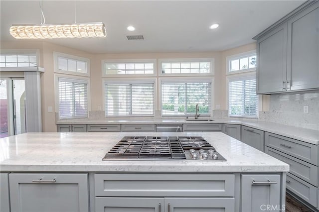 kitchen with gray cabinetry, sink, a center island, and stainless steel gas stovetop