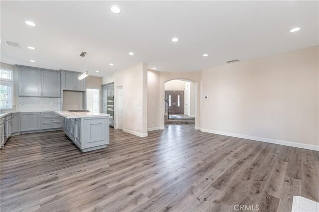 kitchen featuring hardwood / wood-style floors, gray cabinets, stainless steel appliances, and hanging light fixtures