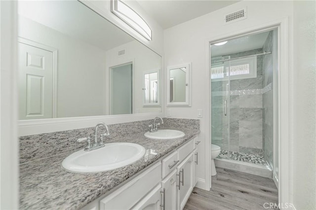 bathroom with vanity, toilet, an enclosed shower, and hardwood / wood-style floors